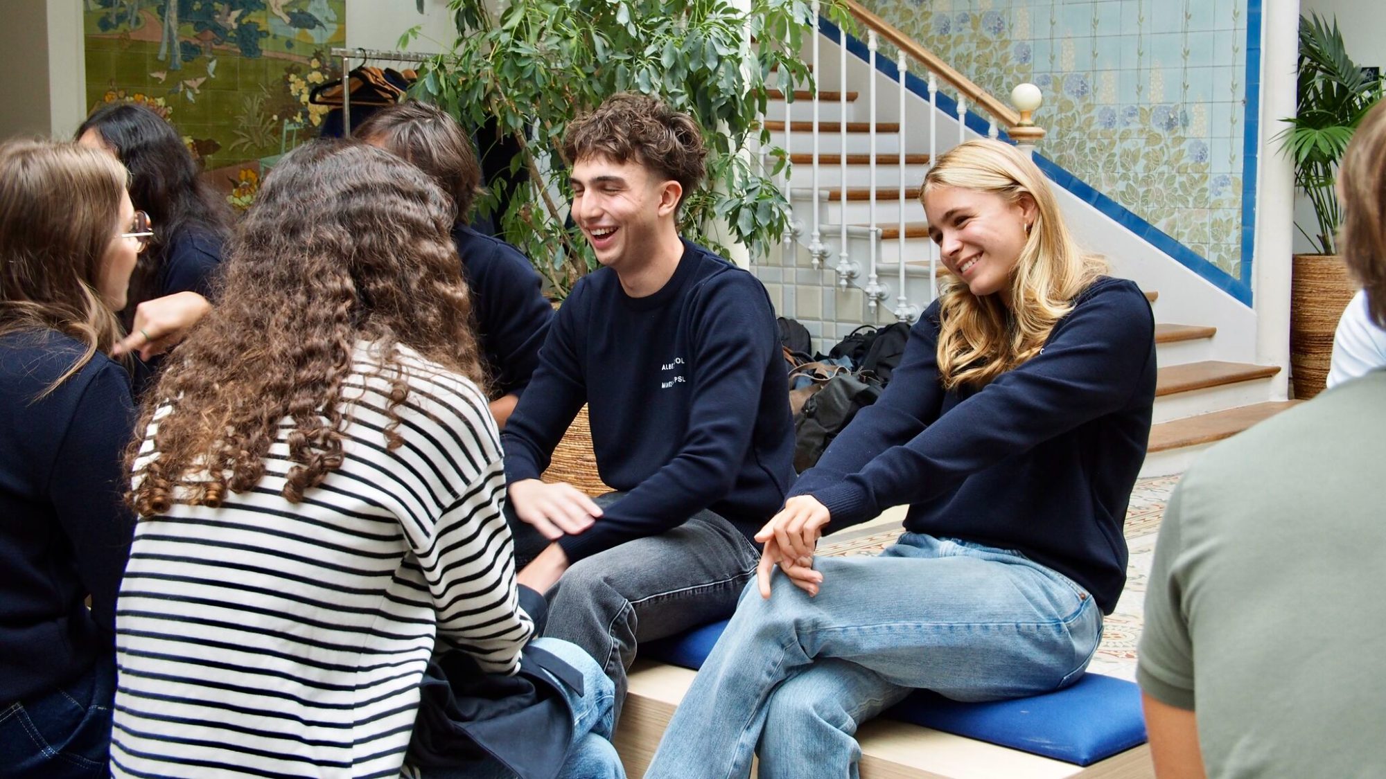 Students laughing together on a bench in a tiled courtyard