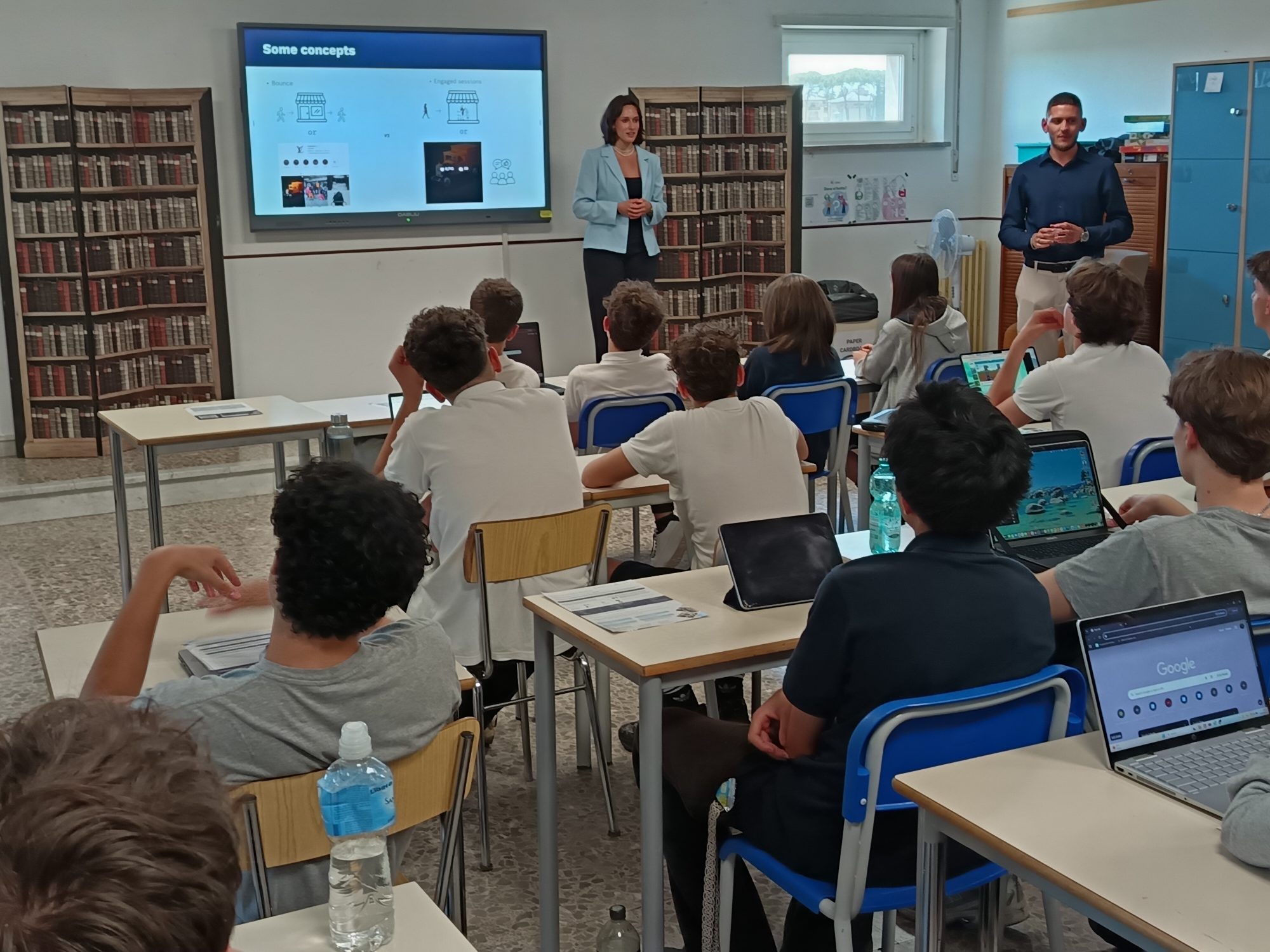 Two ambassadors presenting to a class of students with laptops