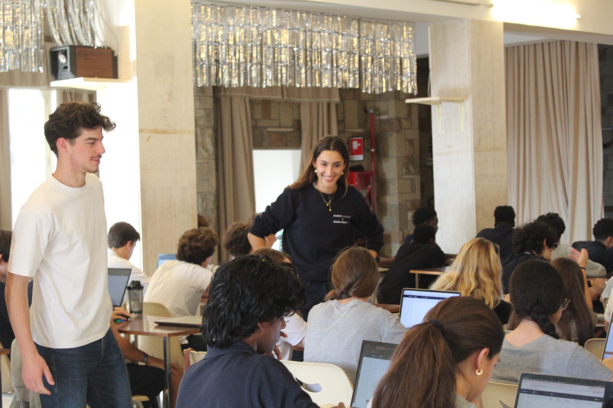 A woman facilitator smiling as she guides high school students working on laptops