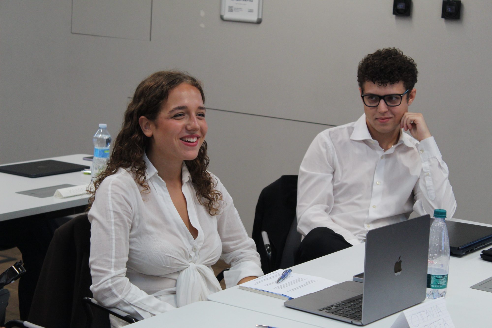 A student laughing at her desk next to a classmate